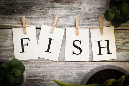 A set of printed cards spelling the word FISH on an aged wooden background.の写真素材