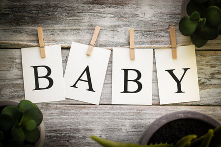 A set of printed cards spelling the word BABY on an aged wooden background.の写真素材