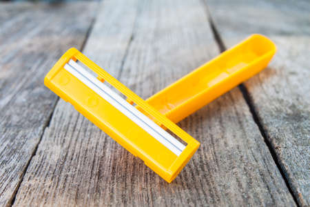 yellow shaving razor on wood backgroundの写真素材