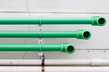 green plastic pipes on the cement wallの写真素材
