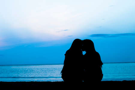 Silhouette of female homosexuals in love beside seaの写真素材