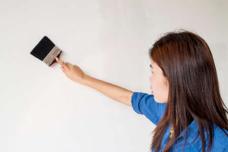 asian woman painting her wall in whiteの写真素材