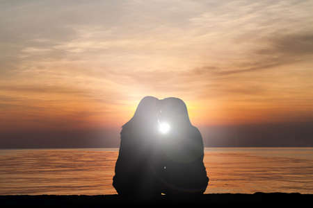 Silhouette of female homosexuals in love beside seaの写真素材