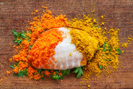 raw chicken wings on chopping board with spicesの写真素材