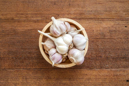 Fresh garlic in wood cup on wood backgroundの写真素材