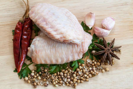 raw chicken wings on chopping board with spicesの写真素材