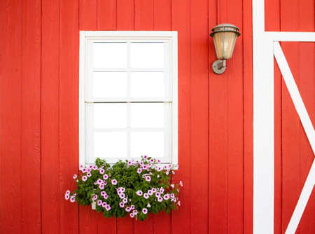 white window on red wall with flower box and lampの写真素材