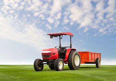 Red tractor with trailer on a grass field