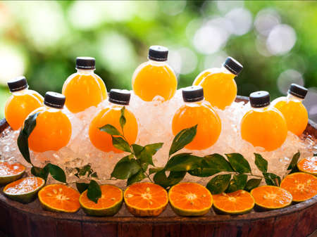 Fresh orange juice and ice on vintage wooden barrel on green backgroundの写真素材