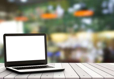 Laptop with blank screen on table with cafe backgroundの写真素材