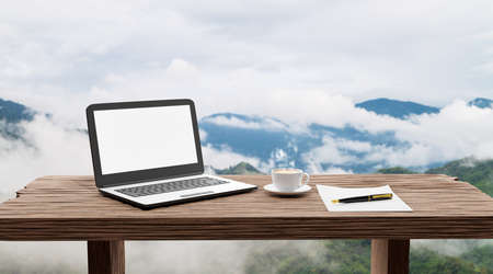 computer notebook and coffee on old table in morning with high mountain background at sunrise, work...
