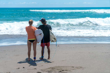 beautiful surf couple on a beach of indonesiaの写真素材