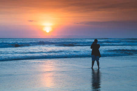 People bathing in the sun in sunset, swiming and playing games on the beach. Tourists on the sand beach in Bali, Indonesiaの写真素材