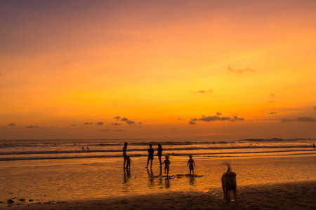 People bathing in the sun in sunset, swiming and playing games on the beach. Tourists on the sand beach in Bali, Indonesiaの写真素材