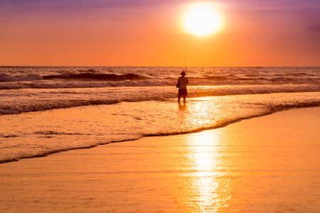 Fisherman silhouette on the beach at colorful sunset in Bali, Indonesiaの写真素材