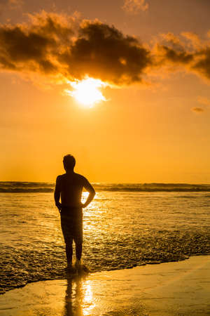 The silhouette of a young man on the beach in Bali, Indonesiaの写真素材