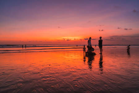 People bathing in the sun in sunset, swiming and playing games on the beach. Tourists on the sand beach in Bali, Indonesiaの写真素材