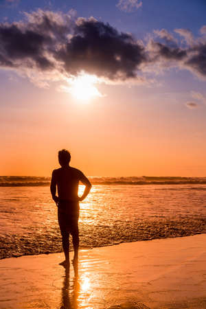 The silhouette of a young man on the beach in Bali, Indonesiaの写真素材