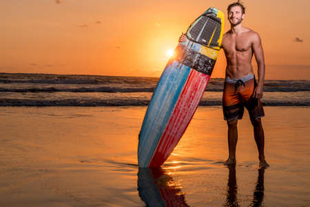 A man is standing with a surf in his hands on the sea shore.