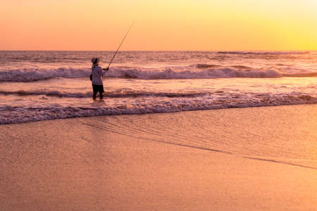 Fisherman silhouette on the beach at colorful sunset in Bali, Indonesiaの写真素材