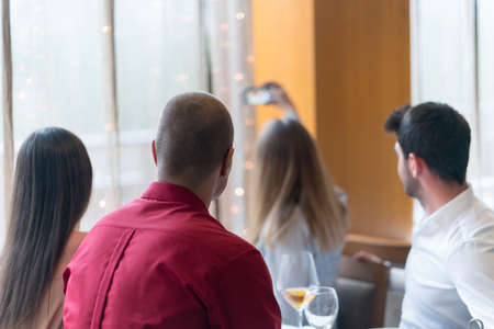 Two couples, friends having launch at restaurant, celebrating and taking selfieの写真素材