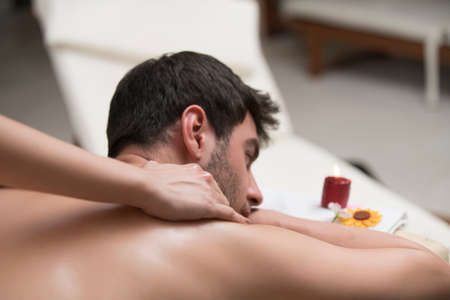 Sports massage. Massage therapist massaging shoulders of a male athlete, working with Trapezius...
