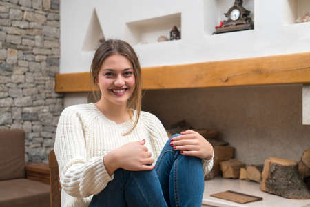 Young woman sitting on sof in mountain cabin, apartment, cottage. Beautifull womanの写真素材
