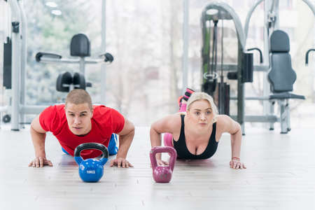 sport, fitness, weightlifting and training concept - group of people with kettlebells exercising in gymの写真素材