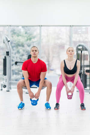 sport, fitness, weightlifting and training concept - group of people with kettlebells exercising in gymの写真素材