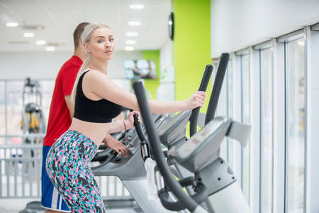 Fitness couple running doing cardio on treamill in fitness center gymの写真素材
