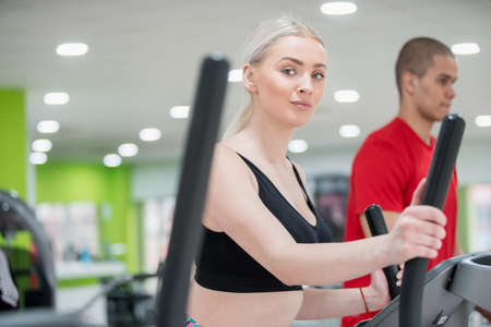 Fitness couple running doing cardio on treamill in fitness center gymの写真素材