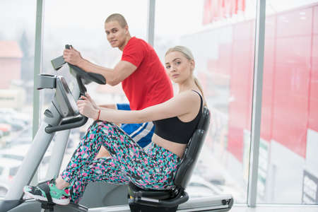 Fitness couple running doing cardio on treamill in fitness center gymの写真素材