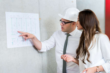 Business man and woman presenting architect blueprint. Making presentation during business meeting in office.の写真素材