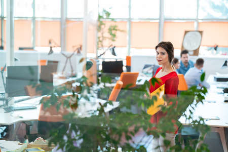 business, startup, people and teamwork concept - happy young woman over creative team in officeの写真素材