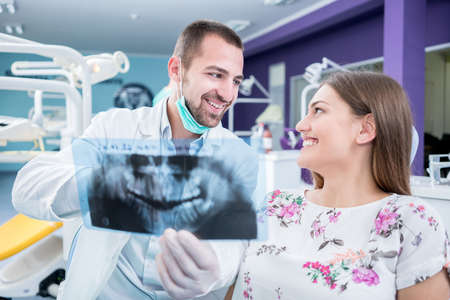 Doctor talking with patient and showing a radiograph in stomatology clinic. Dentist concept.の写真素材