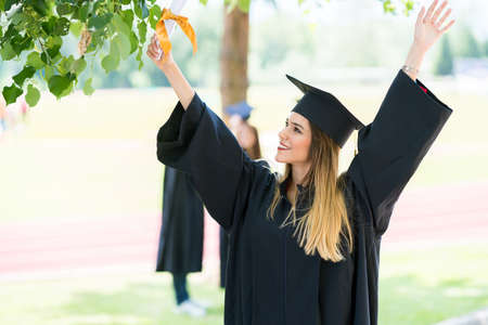 Graduation: Student Standing With Diploma With Friends Behindの写真素材