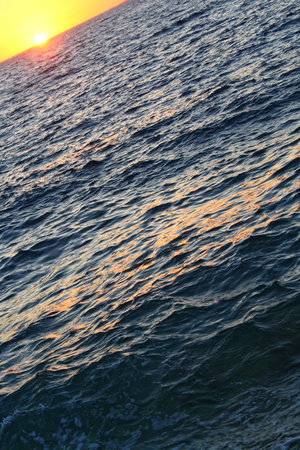 Sunset above the sea with waves, dark waterの写真素材