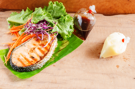 salmon steak on wooden pad and vegetable saladの写真素材