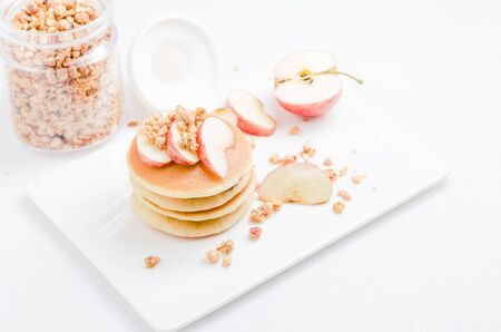 hight key of pancake top with apple and cereal on white plateの写真素材
