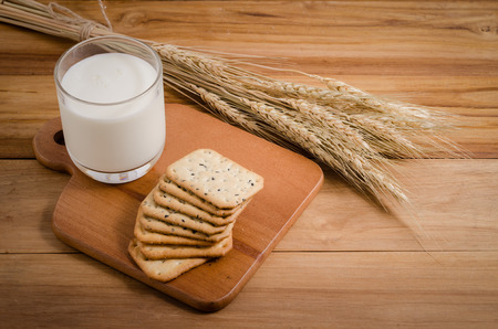glass of milk and square-biscuits on wood, and oat black sesame biscuitsの写真素材