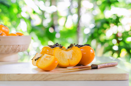 selective focus on yellow persimmon fruits on wood and knife in garden with blur backgroundの写真素材
