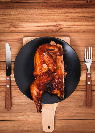 half chicken grilled on wood with fork and steak knife prepared for a meal, main caurse looks delicious.の写真素材