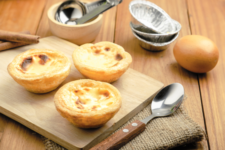 horizontal view of egg tarts put on the wood table with spoonの写真素材
