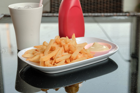 french fried on white plate serving with ketchup and glass of water on table with copy space, unhealthy food.の写真素材