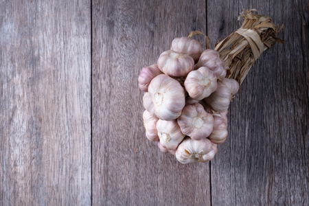 top view of garlic bulbs on old wood table, edible plant used for seasoning, smell is pungent, spicy flavor, a native to Central Asia, called Allium sativum in scientific classification.の写真素材