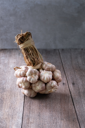 group of dried garlic bulbs put on old wood table, an edible plant used for seasoning, a spicy flovers and pungent, also used of traditional medicineの写真素材