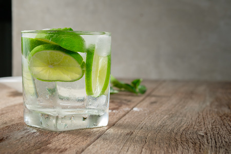 closed up glass of iced lime juice on wood table, infused with sliced lime, souce of Vitamin Cの写真素材