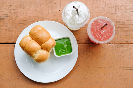 egg custard and some bread in white dish, two glass of beverages put on oragne wood tableの写真素材