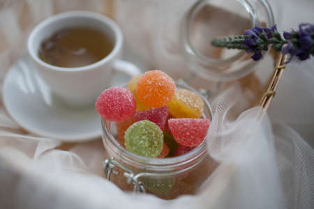 Cup of tea and marmalade in a jar lay in the cart covered with a white silk clothの写真素材