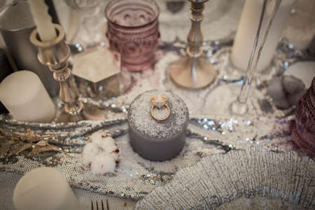 Wedding rings on a candle. Decorations sprinkled with snow.の写真素材